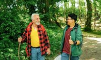 Ein älterer und ein jüngerer Mann im Wald beim Spaziergang. Beide haben einen Gehstock.