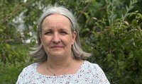 Eine Frau mit schulterlangen, grauen Haaren und einer geblühmten Bluse.