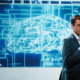 Homme faisant une présentation, cerveau projeté derrière lui sur un écran