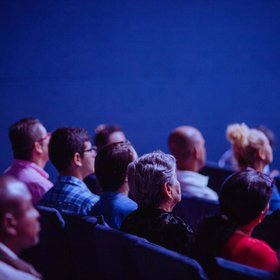 Des personnes assises dans le public dans une salle de conférence