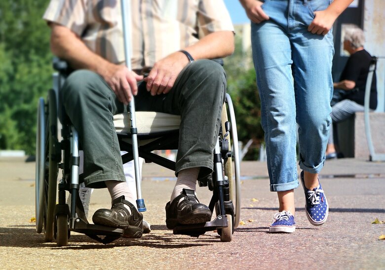 Une personne en chaise roulante se déplace avec une autre personne