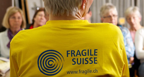 Une personne de dos portant un t-shirt de FRAGILE Suisse