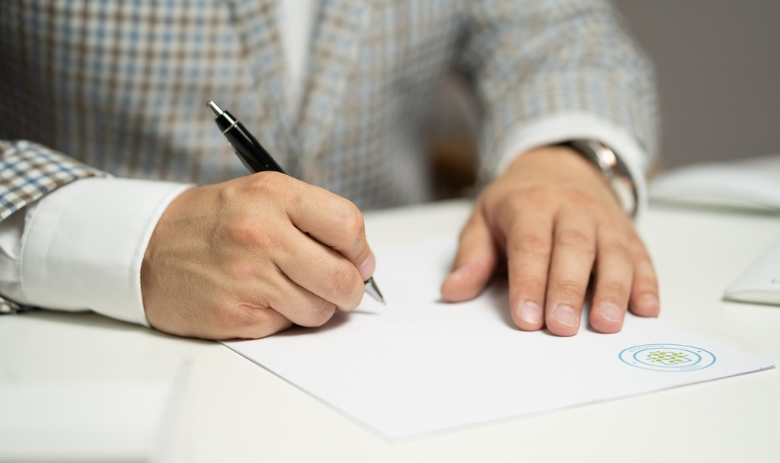 Ein Mann schreibt von Hand auf ein Blatt Papier.