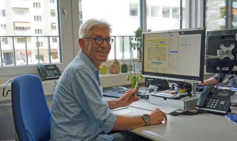 Un homme riant assis face à un bureau