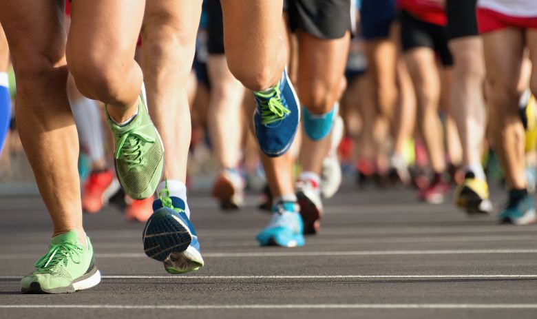 Ausschnitt der Beine von zahlreichen Menschen, die Sportkleidung tragen und in Bewegung sind.